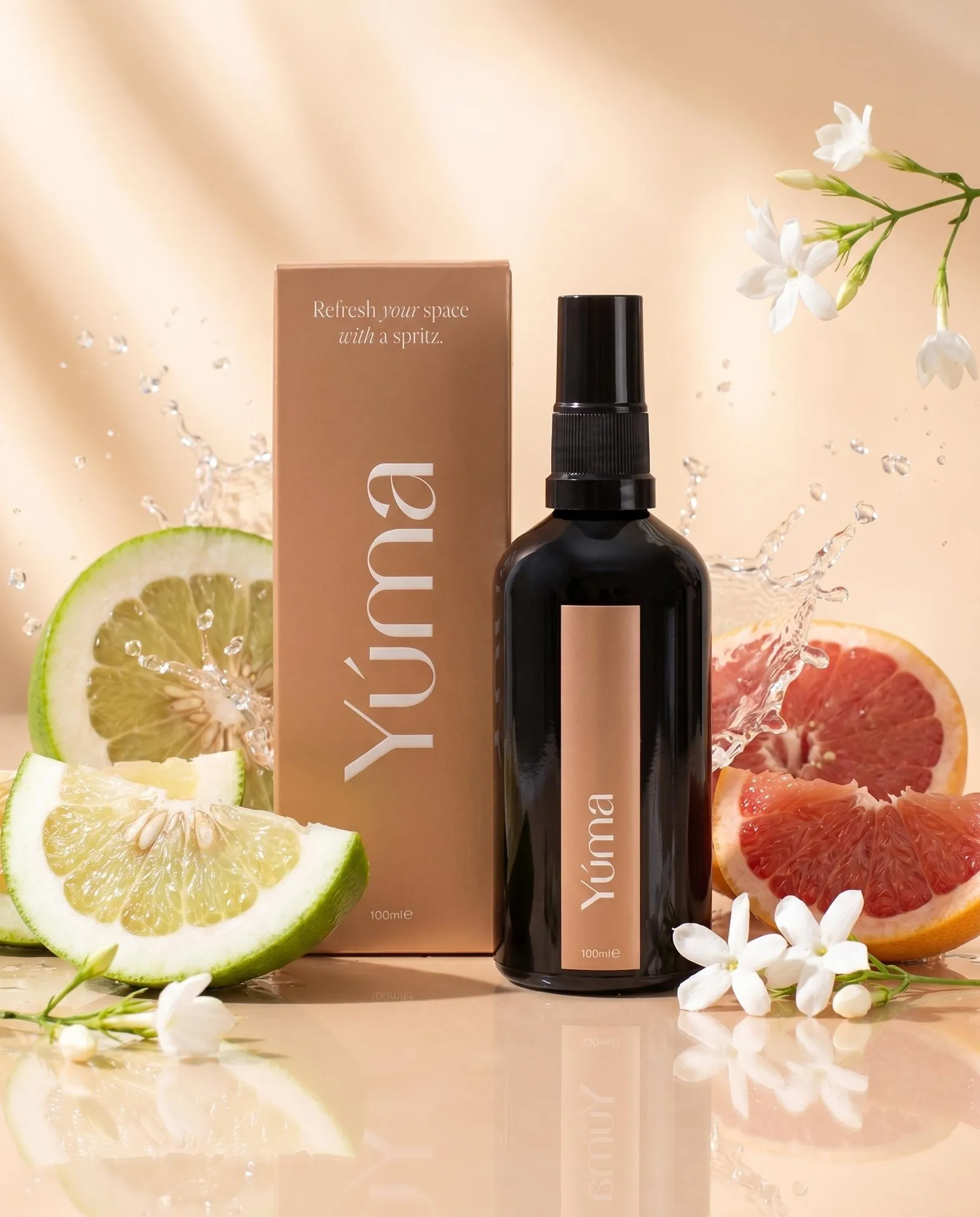 YUMA Hesperides Jasmine dark spray bottle and box among citrus slices, jasmine flowers, and water droplets.