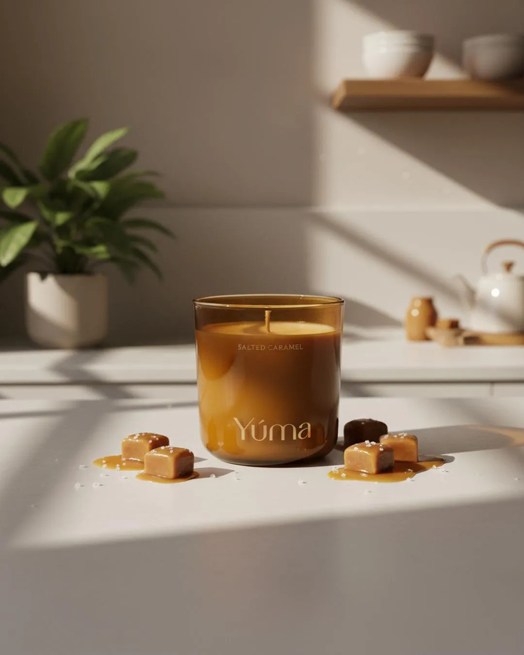 YUMA Salted Caramel candle in a brown glass vessel among caramel cubes and flakes of salt.