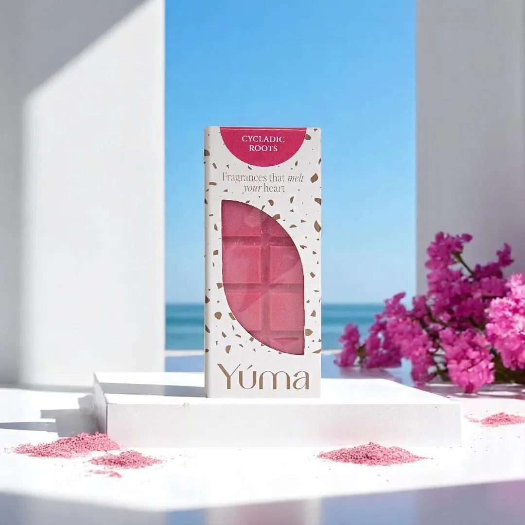 YUMA Cycladic Roots pink wax melts in white packaging, with the sea and flowers in the background.
