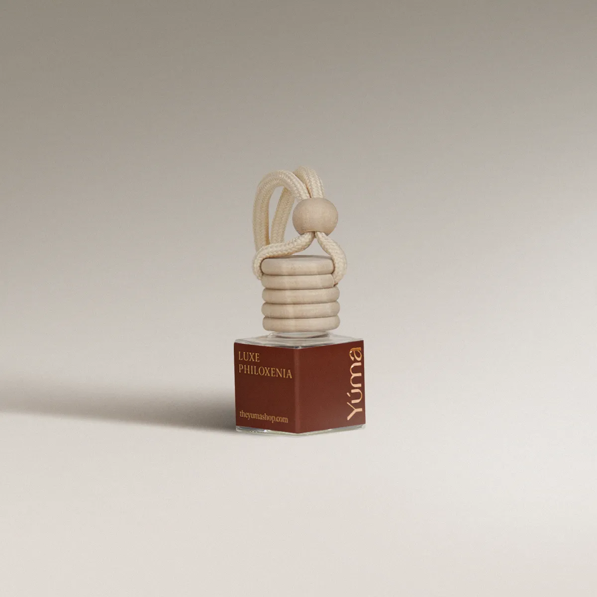 YUMA Luxe Philoxenia glass car diffuser with a wooden cap and hanging rope.