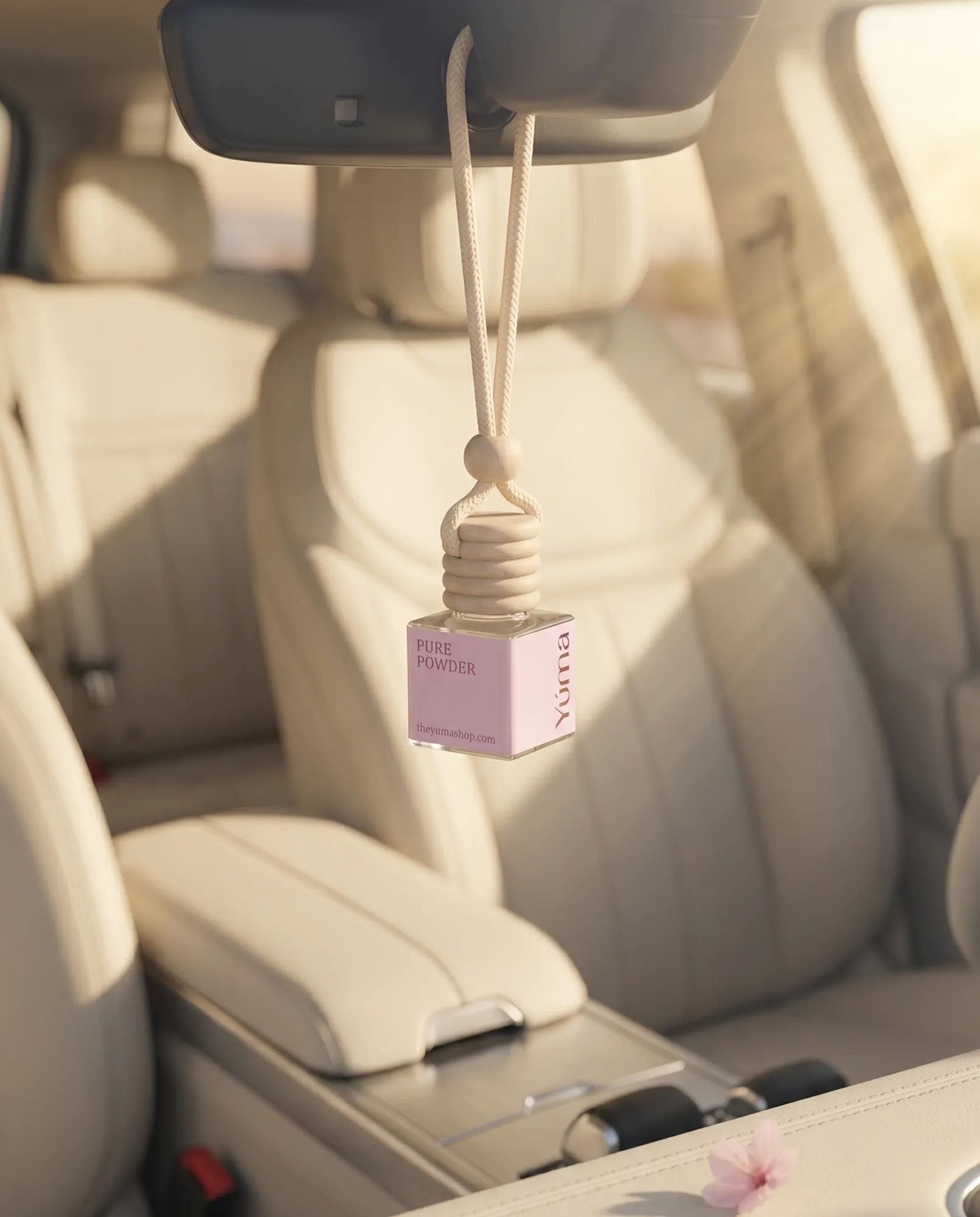 YUMA Pure Powder hanging car air freshener with a wooden cap, displayed on the rearview mirror of a beige car interior.