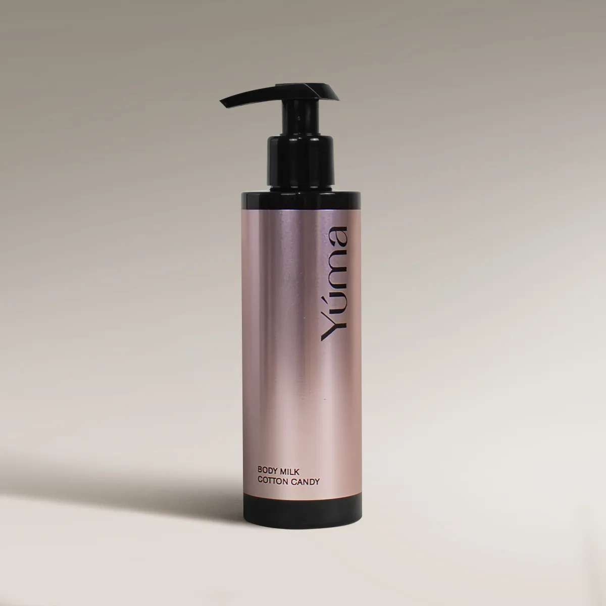YUMA Cotton Candy Body Milk in a metallic pink bottle with a black pump on a beige background.