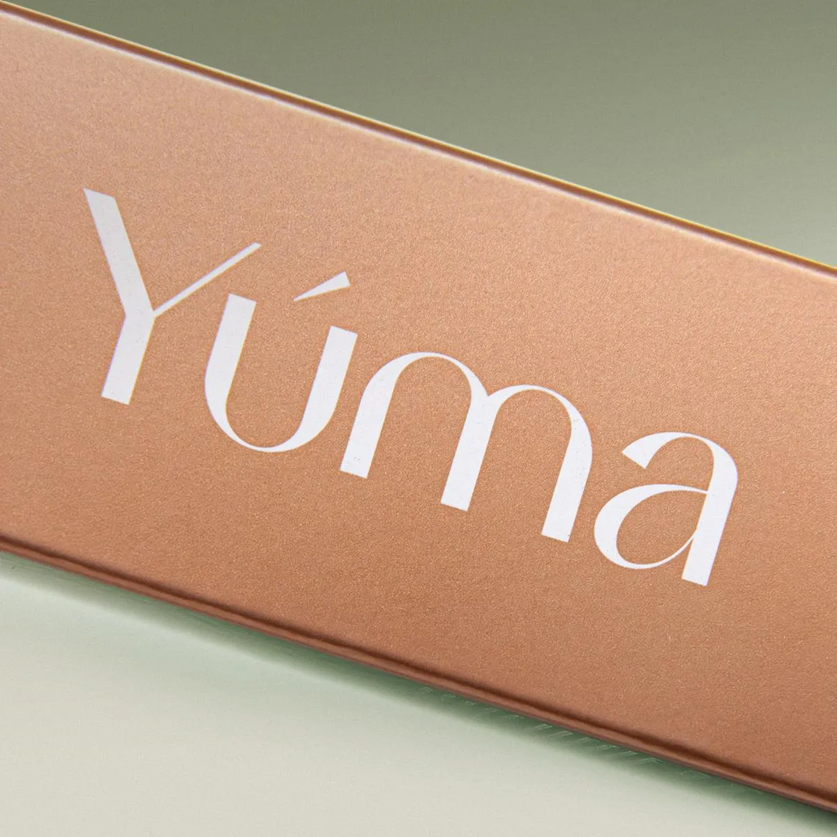 Close-up of the YUMA logo in white lettering on a copper metallic surface.