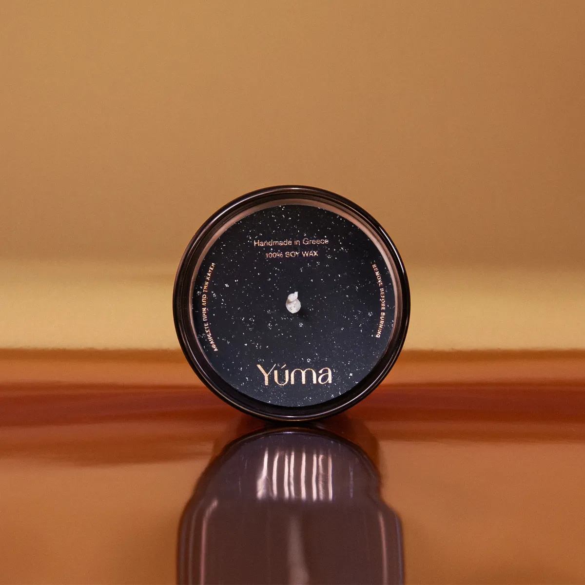 Top view of a YUMA Salted Caramel candle with a black cover on a brown background.