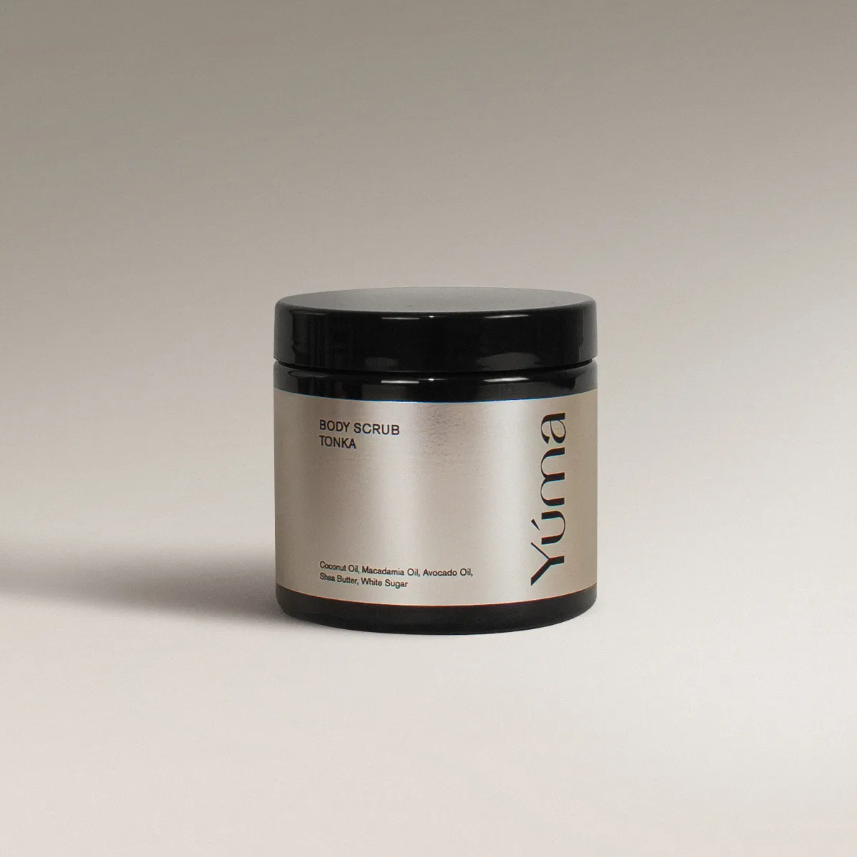 YUMA Tonka scented Body Scrub in a black jar with a silver label on a grey background.