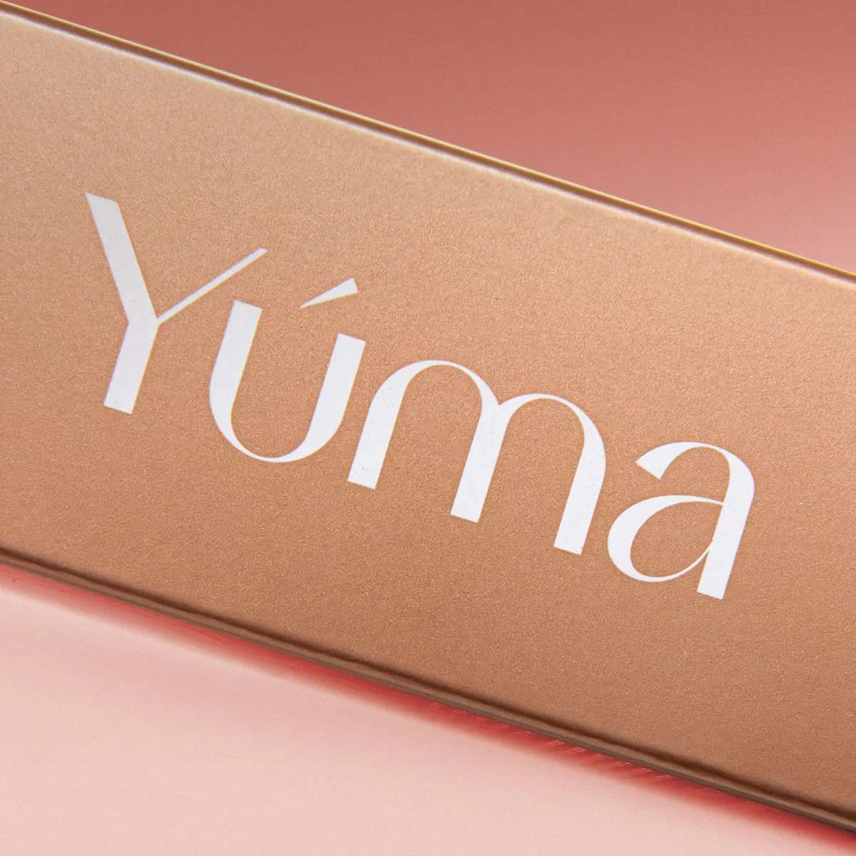Close-up of the YUMA logo in white on a gold metallic surface.