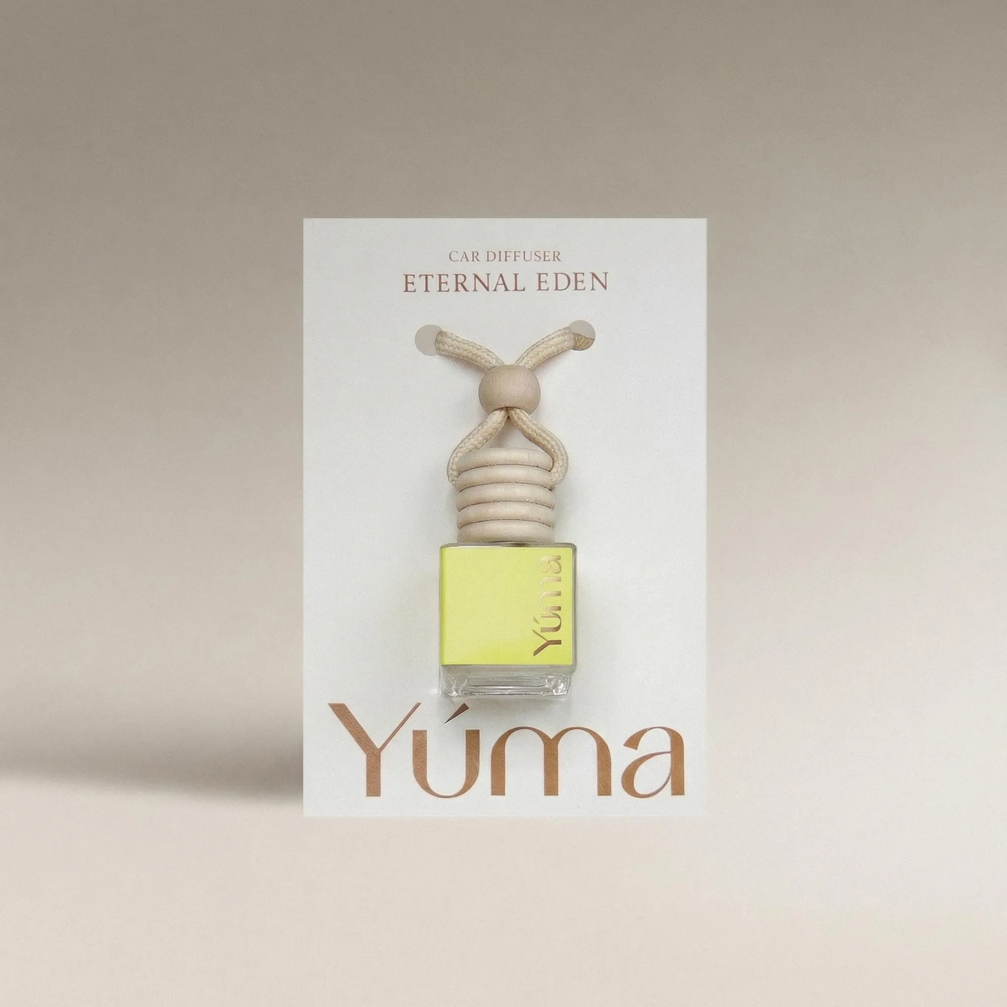 YUMA Eternal Eden Car Diffuser small glass bottle filled with yellow liquid and fitted with a wooden cap.