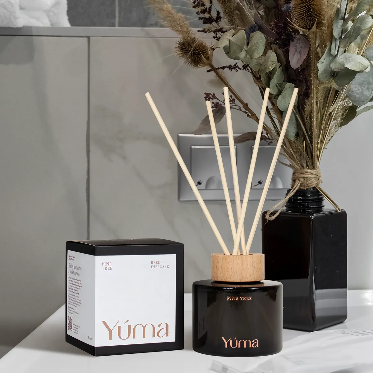 YUMA Pine Tree reed diffuser in a dark glass bottle next to its packaging.