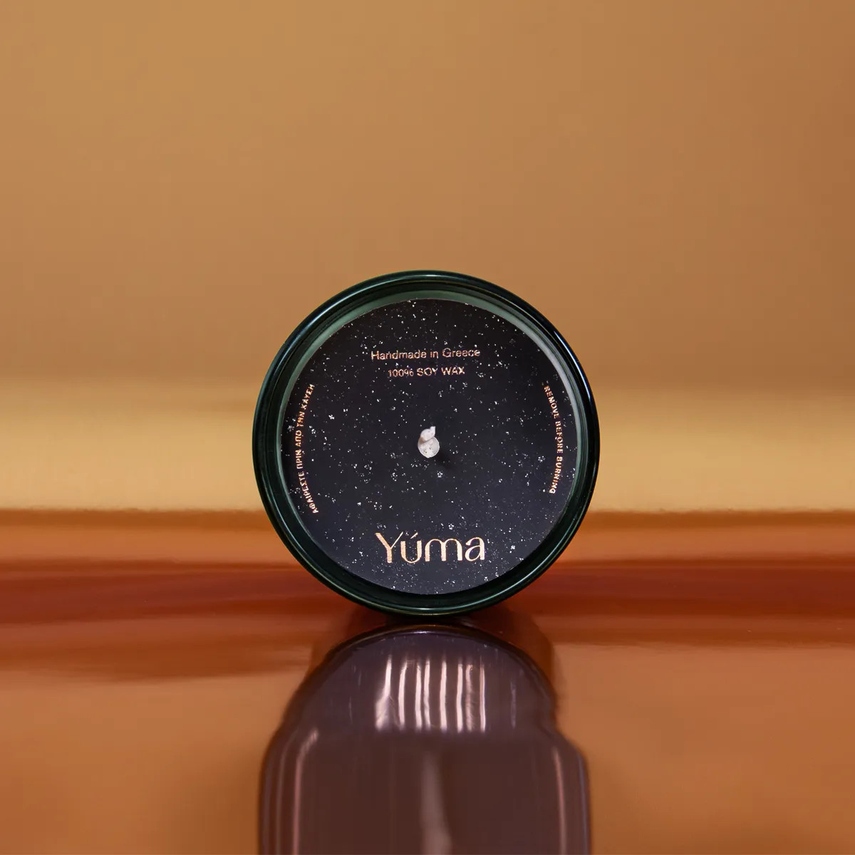 YUMA Pine Tree candle in a dark green glass vessel with a black cover and gold lettering.