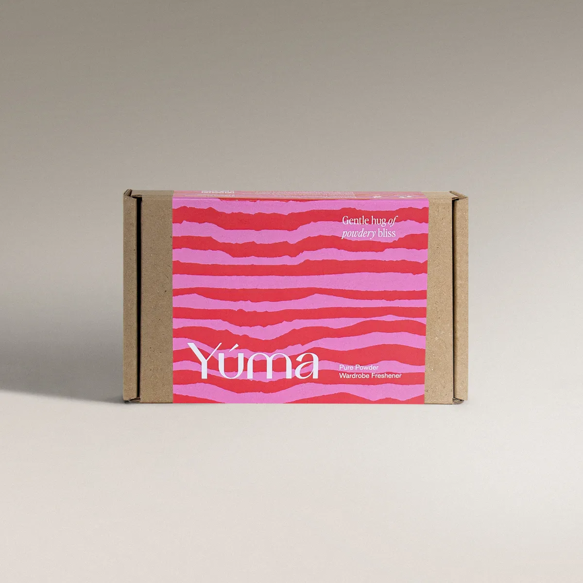 YUMA Pure Powder paper packaging with pink and red stripes on a grey background.