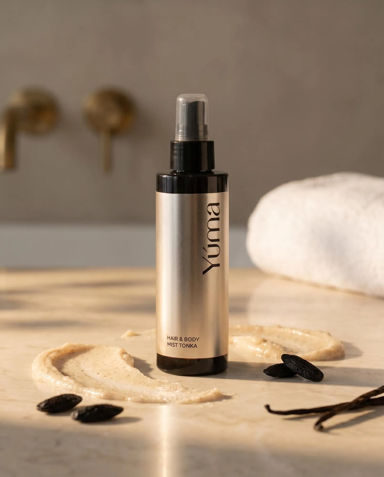 YUMA Tonka Hair & Body Mist in a gold bottle beside body cream and seeds as visual references to the fragrance.