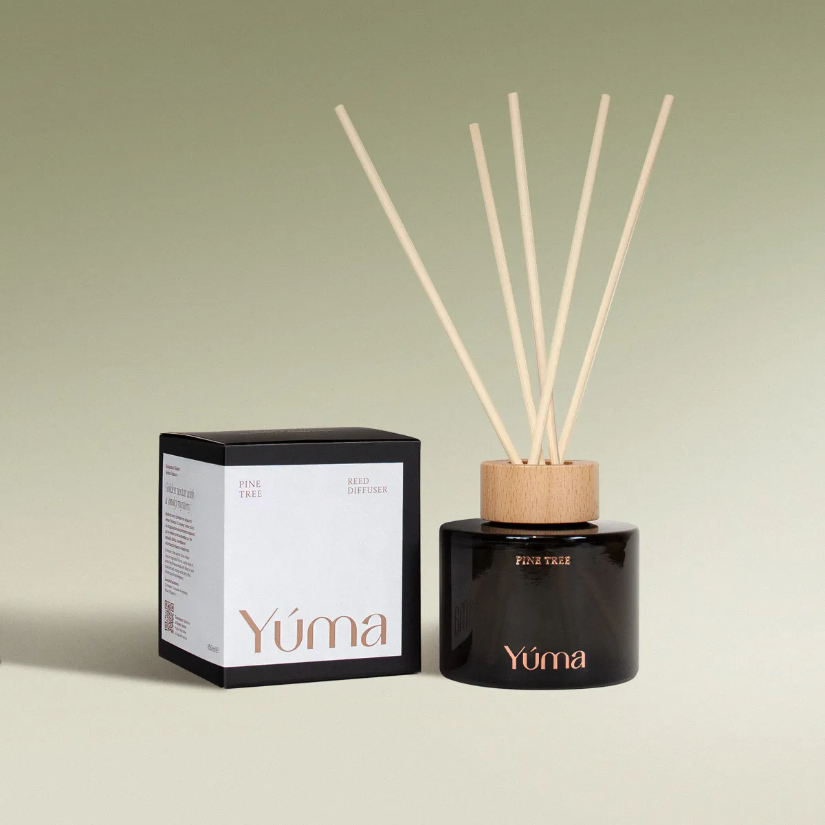 YUMA Pine Tree reed diffuser in a dark glass bottle next to its paper packaging.