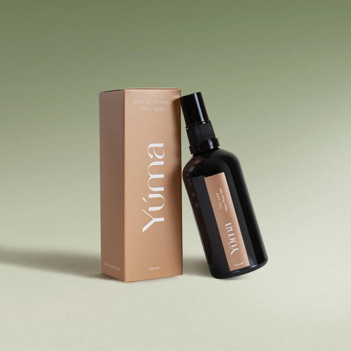 YUMA Fabric Mist Fig Sap dark glass bottle next to its brown paper packaging.