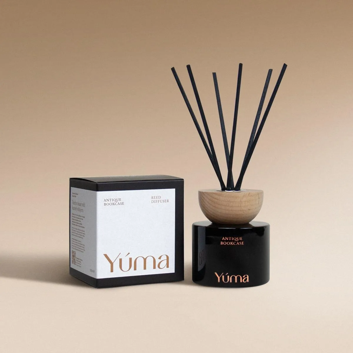 YUMA Antique Bookcase reed diffuser in a black glass bottle with a wooden cap, next to its paper packaging.