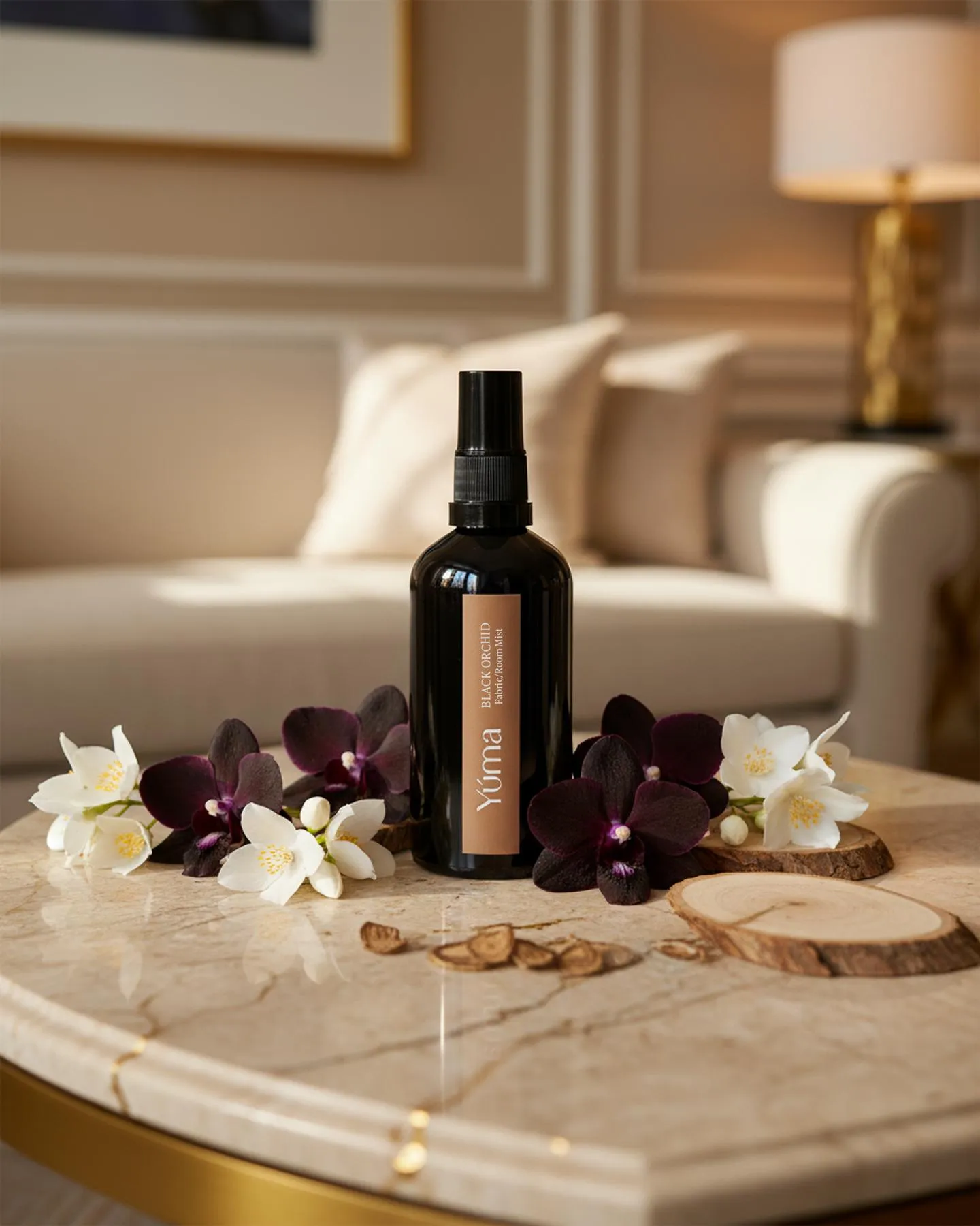 YUMA Fabric Mist Black Orchid black bottle surrounded by dark orchids and white flowers.