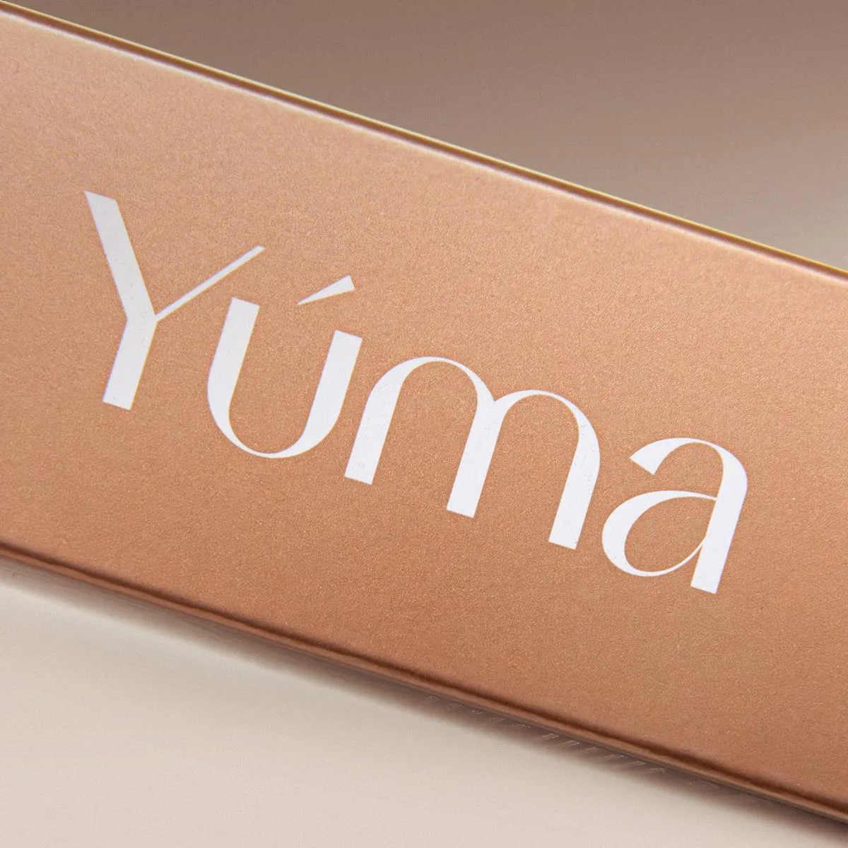 Close-up of the YUMA Luxe Philoxenia gold packaging with the logo in white.
