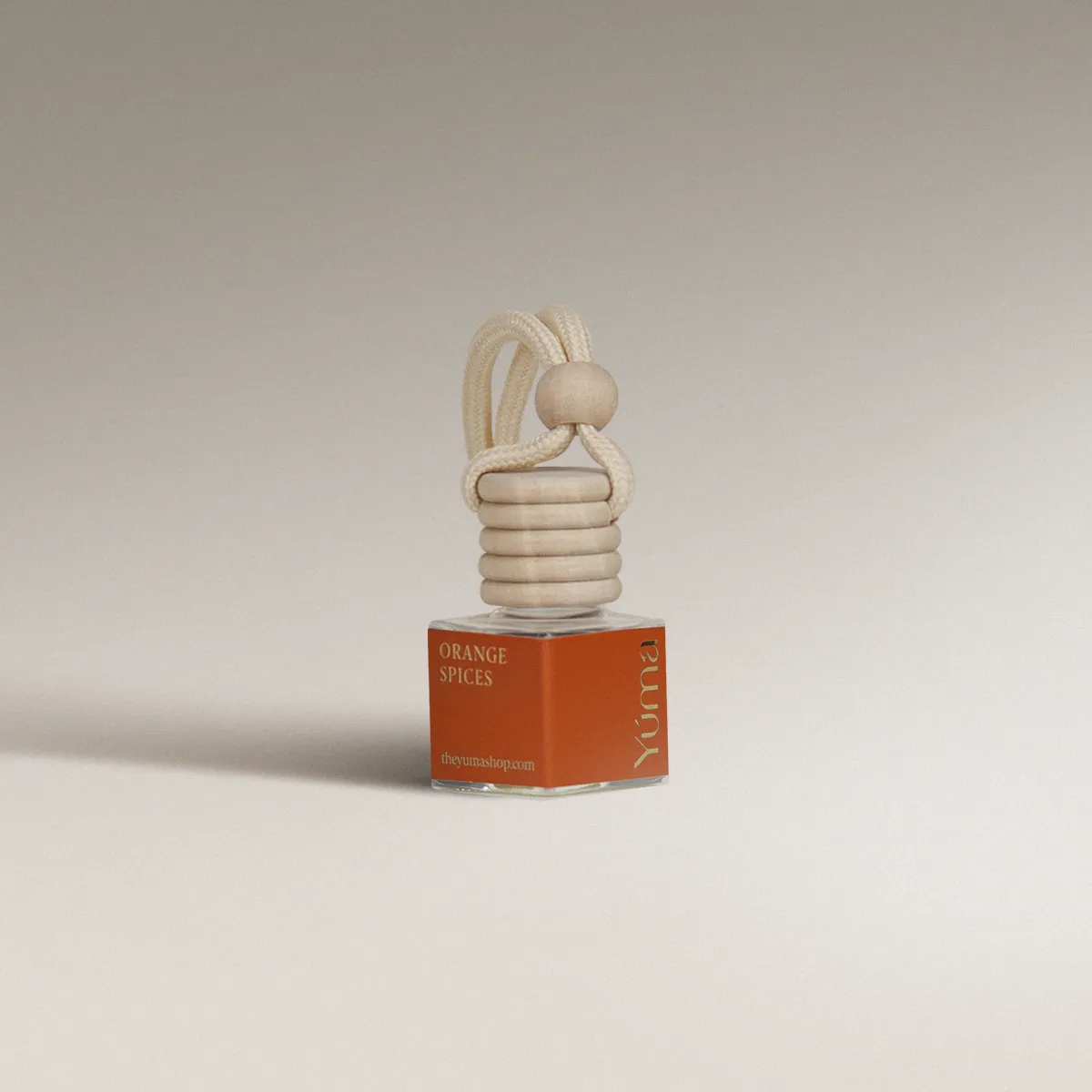 YUMA Orange Spices glass car diffuser with an orange label, wooden cap, and rope cord.