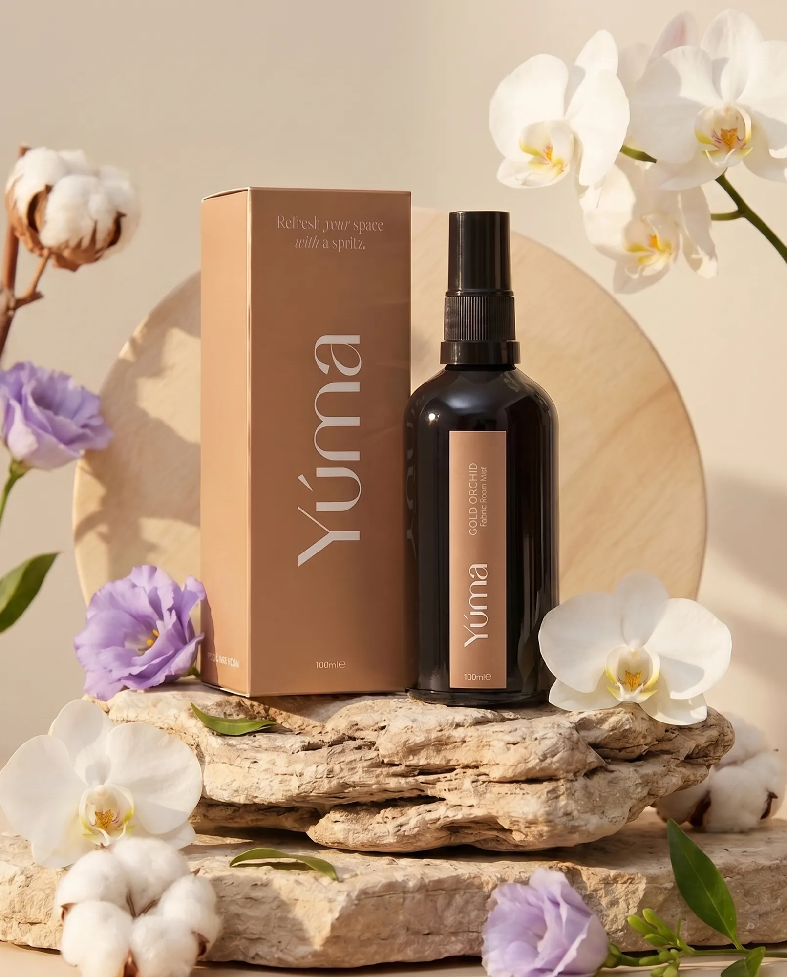 YUMA Gold Orchid Fabric Room Mist bottle beside its packaging, surrounded by white orchids.