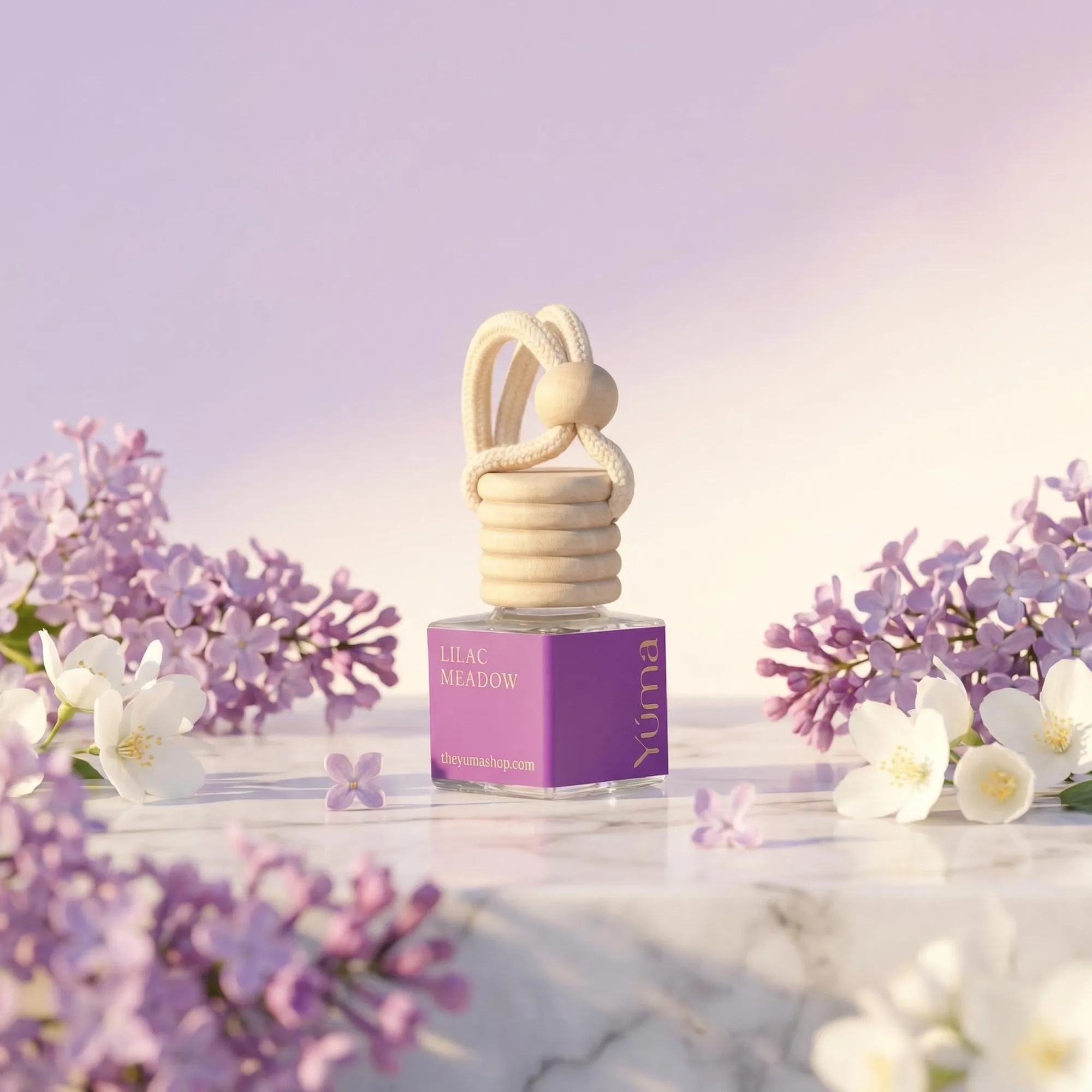 YUMA Lilac Meadow purple Car Diffuser on a marble surface, surrounded by lilac and white blossoms.