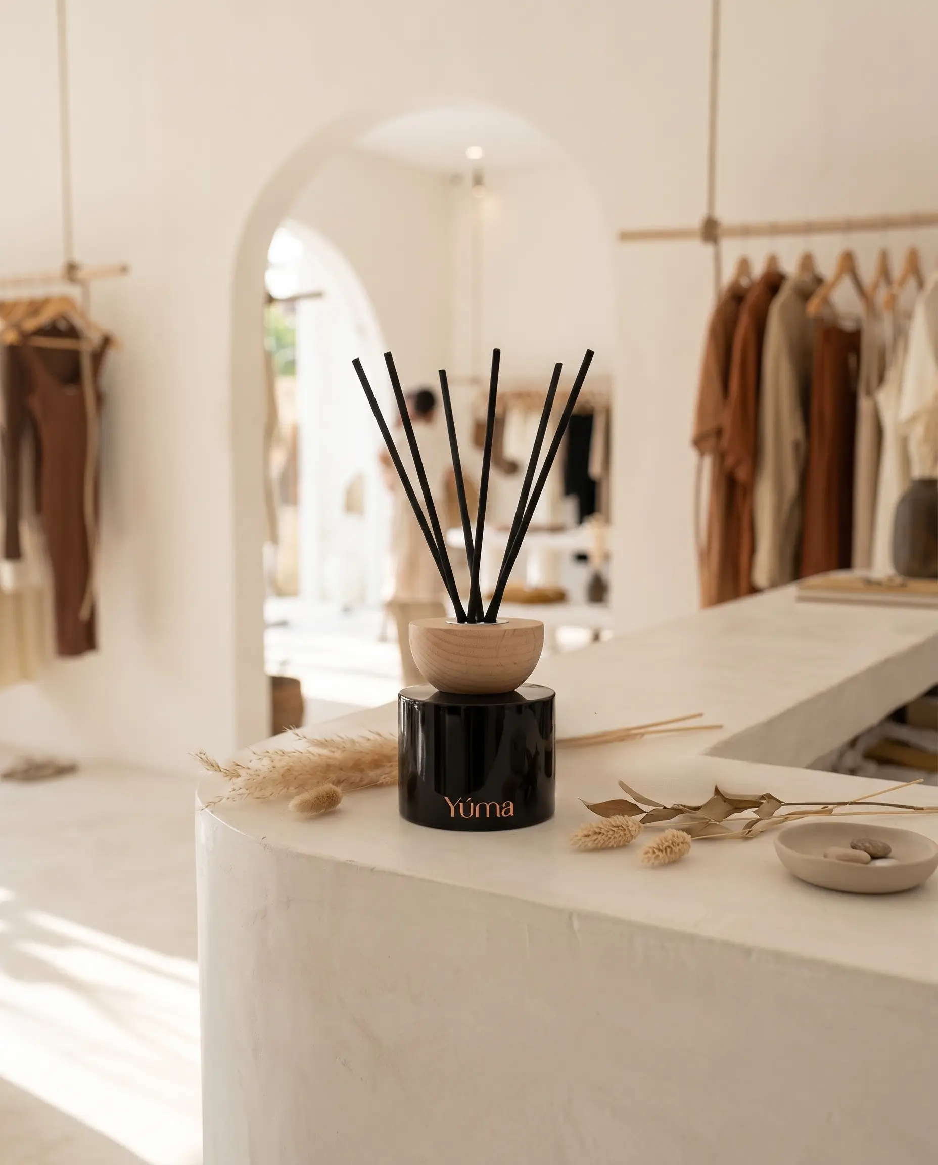 Glass reed diffuser with reeds on a warm wood surface. Glass reed diffuser with reeds on a warm wood surface.