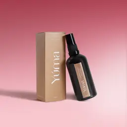 Cherry Sonnet Fabric Mist YUMA Cherry Sonnet Fabric Mist black bottle next to its beige packaging on a pink background.