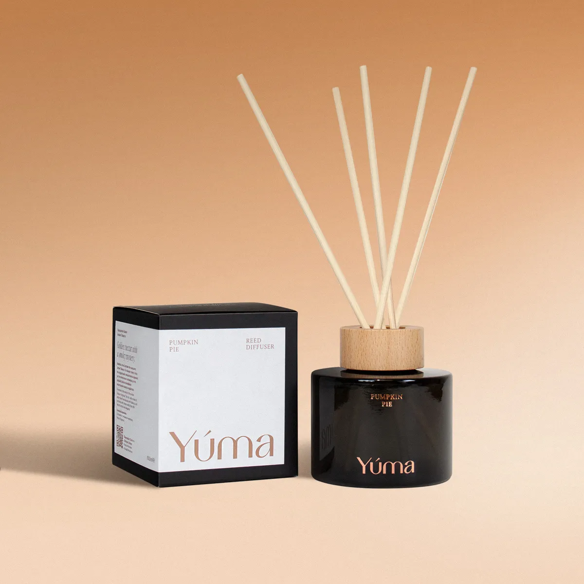 Room Fragrance - Pumpkin Pie - Reed Diffuser - Pumpkin Scent YUMA Pumpkin Pie reed diffuser in a dark glass bottle beside its paper packaging.