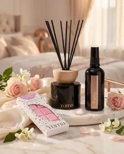 Bedroom Set YUMA Pure Powder Reed Diffuser, Fabric/Room Mist and Snap Bar displayed next to pink roses.