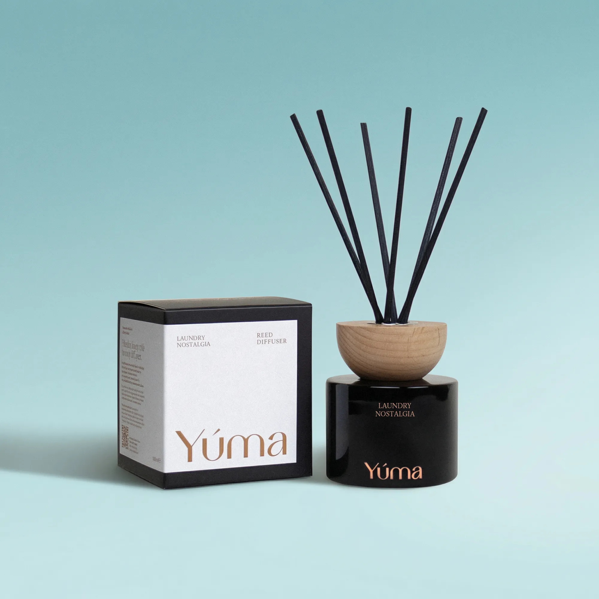 Laundry Nostalgia Reed Diffuser YUMA Laundry Nostalgia reed diffuser in a black glass vessel next to its paper packaging.