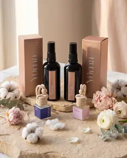 Car Set YUMA Fresh Linen and Pure Powder Fabric/Room Mists with their two matching Car Diffusers among flowers.
