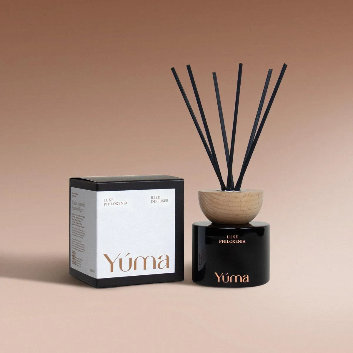 Luxe Philoxenia Reed Diffuser YUMA Luxe Philoxenia reed diffuser in a black glass vessel next to its packaging.